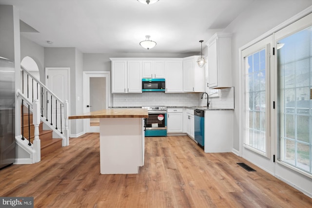 kitchen featuring wood counters, appliances with stainless steel finishes, pendant lighting, light hardwood / wood-style flooring, and white cabinets