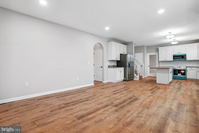 kitchen with tasteful backsplash, white cabinetry, light hardwood / wood-style flooring, and stainless steel appliances