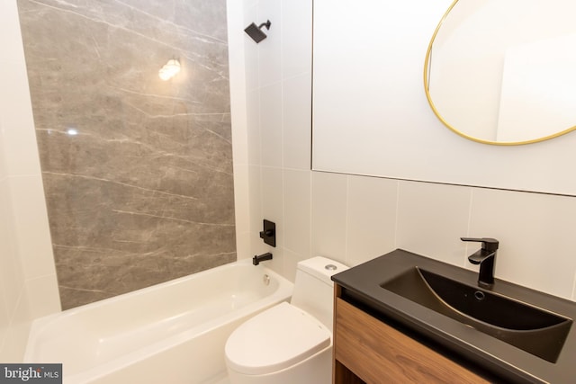 full bathroom featuring tile walls, vanity, tiled shower / bath combo, and toilet