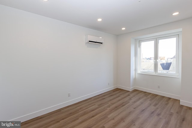 unfurnished room with an AC wall unit and light hardwood / wood-style flooring