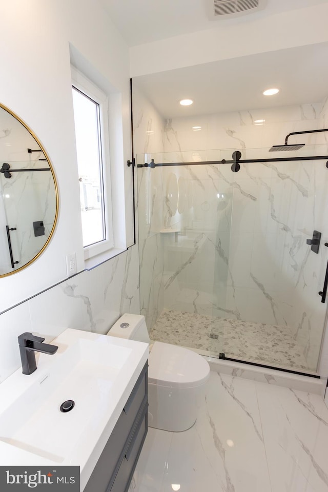 bathroom featuring vanity, toilet, a shower with door, and tile walls