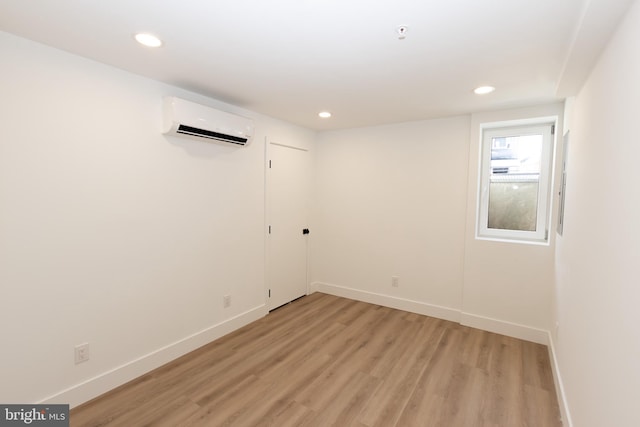 empty room featuring a wall mounted air conditioner and light hardwood / wood-style flooring