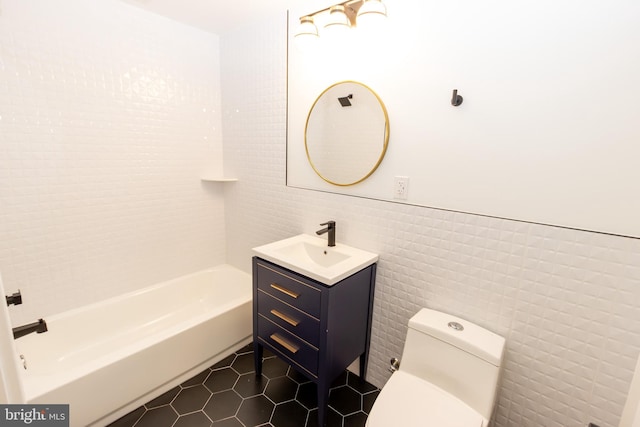 bathroom featuring vanity, a bathing tub, tile patterned flooring, toilet, and tile walls