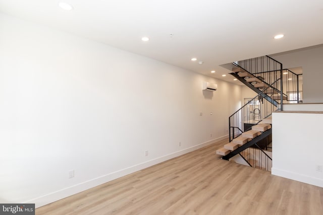 unfurnished living room featuring a wall mounted air conditioner and light wood-type flooring