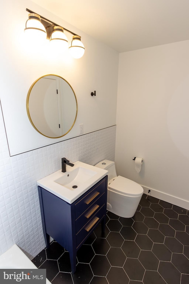 bathroom featuring tile patterned floors, vanity, toilet, and tile walls