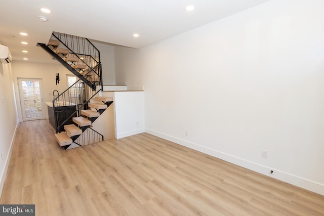 interior space featuring a wall mounted air conditioner and light wood-type flooring