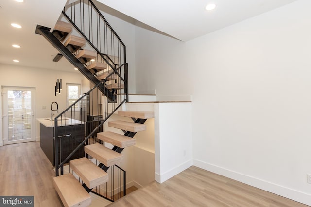 staircase featuring wood-type flooring and sink