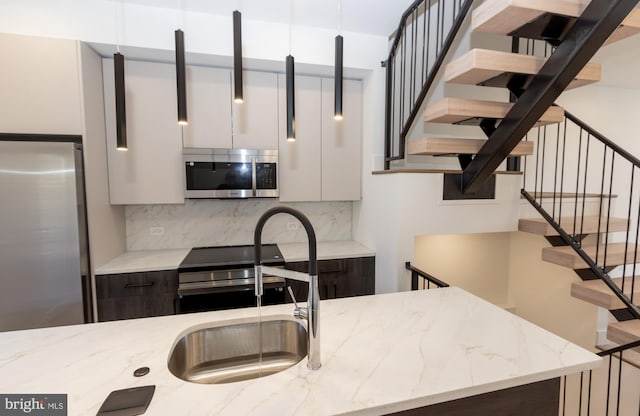 kitchen with white cabinetry, dark brown cabinets, stainless steel appliances, and light stone counters