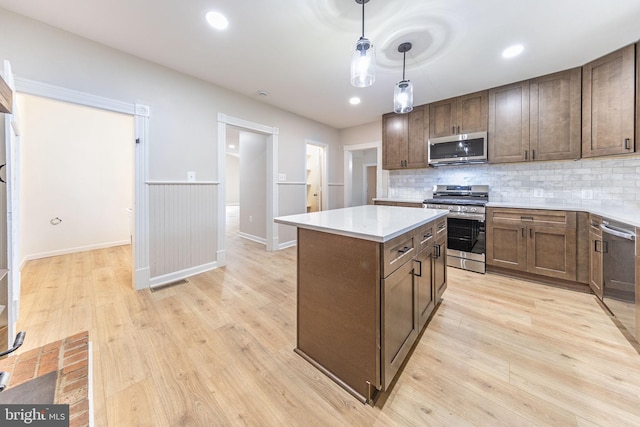 kitchen with a center island, stainless steel appliances, light hardwood / wood-style flooring, and hanging light fixtures