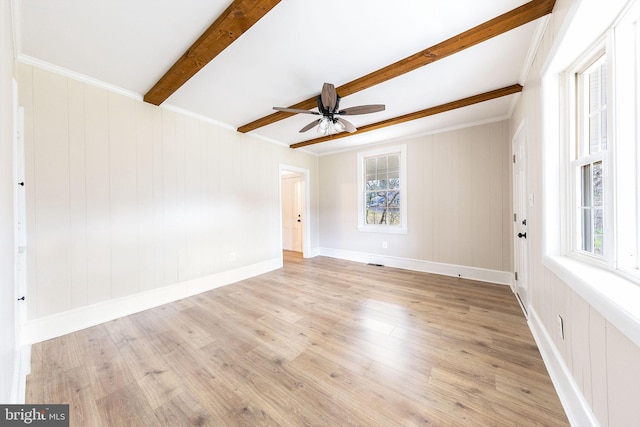 empty room with plenty of natural light, beam ceiling, light wood-type flooring, and ceiling fan