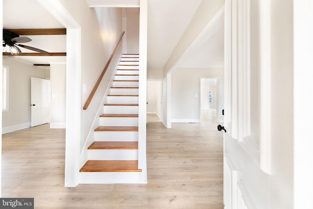 stairway with ceiling fan, beam ceiling, and wood-type flooring