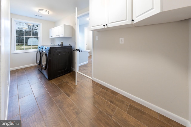 clothes washing area featuring washer and dryer, dark hardwood / wood-style floors, and cabinets