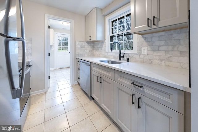 kitchen featuring appliances with stainless steel finishes, tasteful backsplash, sink, light tile patterned floors, and gray cabinets