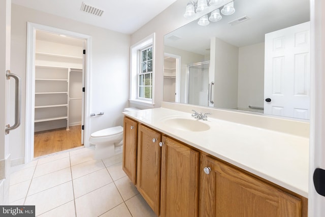 bathroom with tile patterned flooring, vanity, toilet, and an enclosed shower