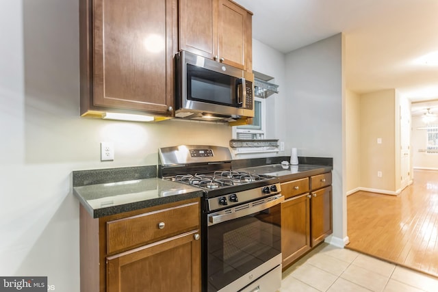 kitchen with appliances with stainless steel finishes, light wood-type flooring, and dark stone counters