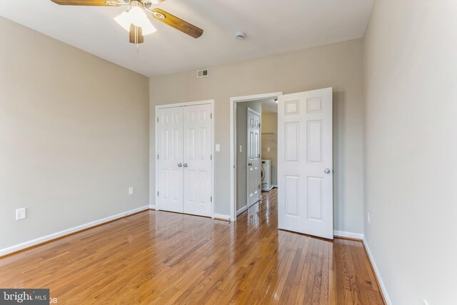 unfurnished bedroom with hardwood / wood-style flooring, ceiling fan, washing machine and dryer, and a closet