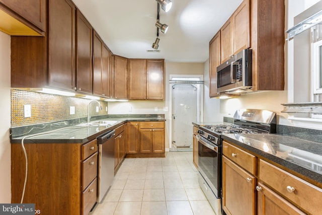 kitchen with sink, rail lighting, tasteful backsplash, light tile patterned flooring, and appliances with stainless steel finishes