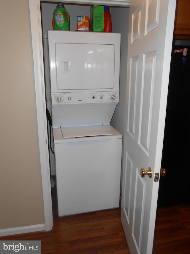 clothes washing area with stacked washer / dryer and dark wood-type flooring