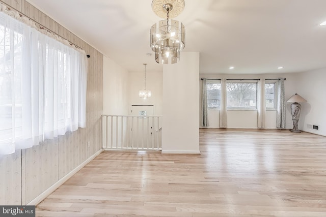 unfurnished living room with a chandelier and light hardwood / wood-style flooring