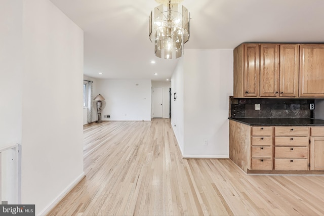 kitchen with backsplash, light hardwood / wood-style flooring, a chandelier, and decorative light fixtures