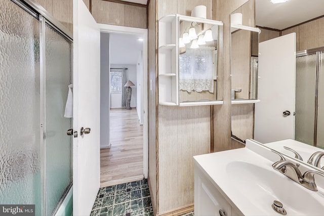 bathroom with wooden walls, vanity, hardwood / wood-style flooring, and a shower with shower door