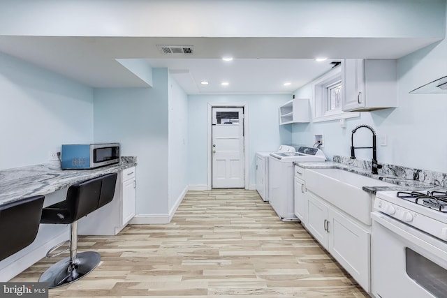 kitchen with white cabinets, light stone countertops, separate washer and dryer, and light hardwood / wood-style flooring