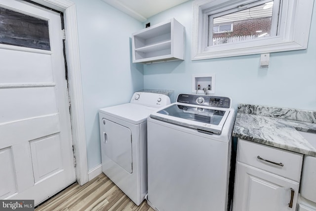 clothes washing area featuring separate washer and dryer and light hardwood / wood-style floors