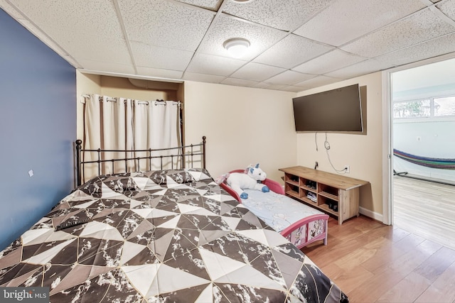 bedroom featuring hardwood / wood-style floors and a drop ceiling