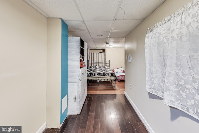 hallway with a paneled ceiling and dark hardwood / wood-style flooring