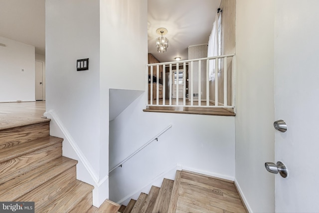 staircase featuring a notable chandelier and hardwood / wood-style flooring