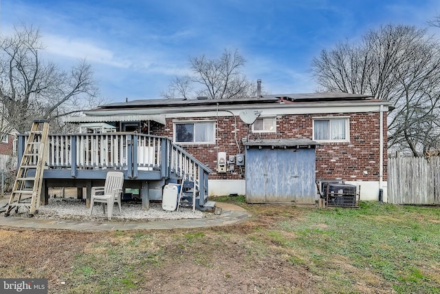 rear view of house featuring solar panels, a yard, a wooden deck, and central AC