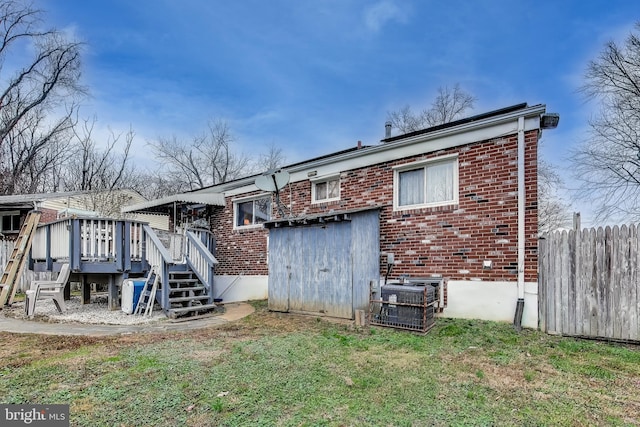 back of property with central AC unit, a deck, and a yard