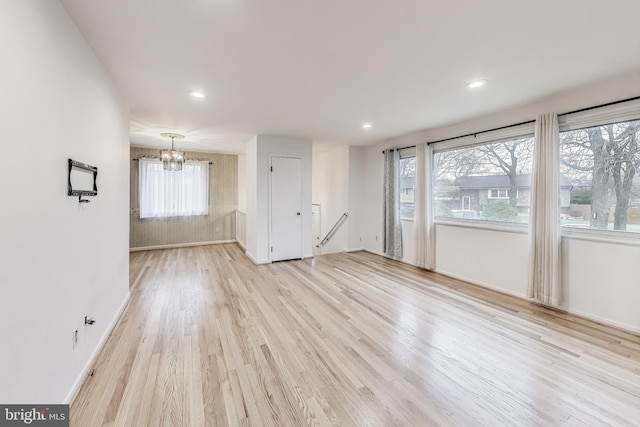 unfurnished room with a notable chandelier and light wood-type flooring