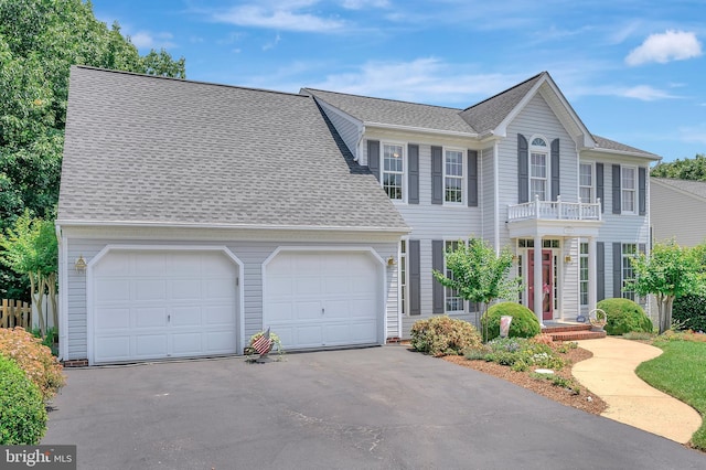 colonial inspired home featuring a garage and a balcony