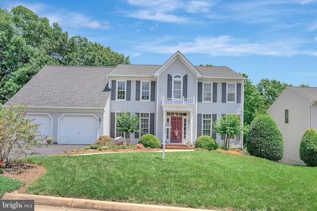 colonial home featuring a balcony, a garage, and a front lawn