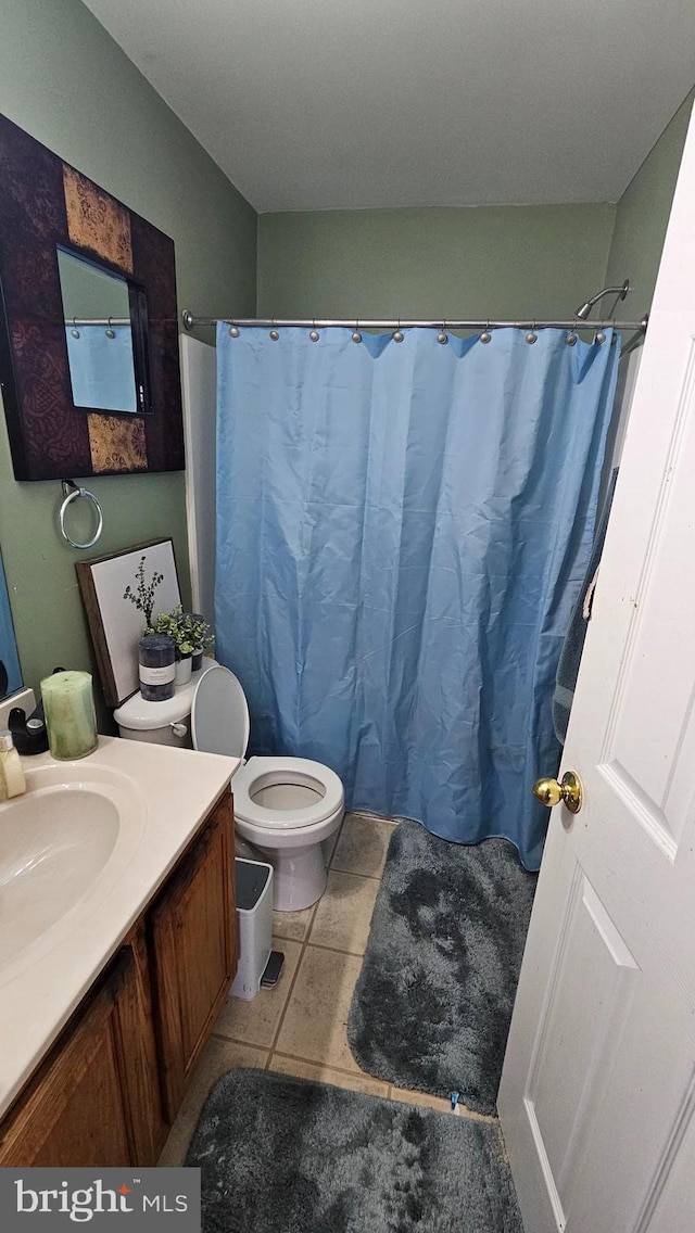 bathroom with walk in shower, tile patterned floors, toilet, and vanity