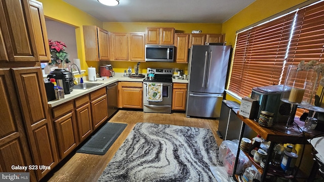 kitchen with appliances with stainless steel finishes, sink, and light hardwood / wood-style floors