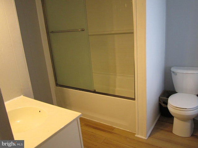 full bathroom featuring hardwood / wood-style flooring, vanity, toilet, and bath / shower combo with glass door