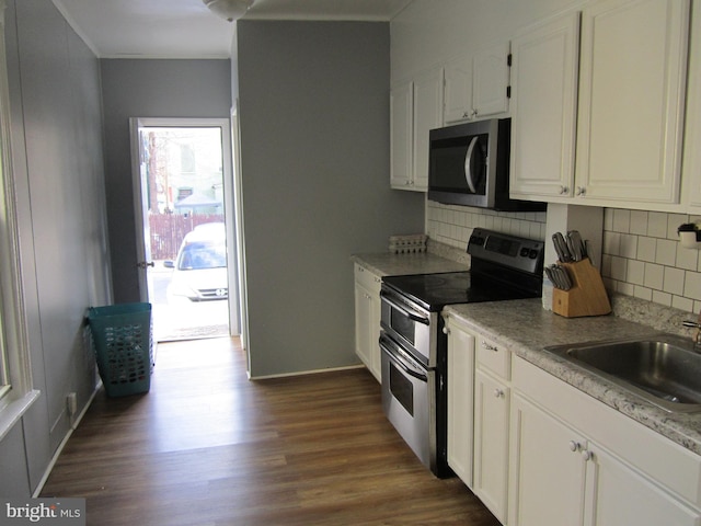 kitchen with backsplash, sink, appliances with stainless steel finishes, dark hardwood / wood-style flooring, and white cabinetry