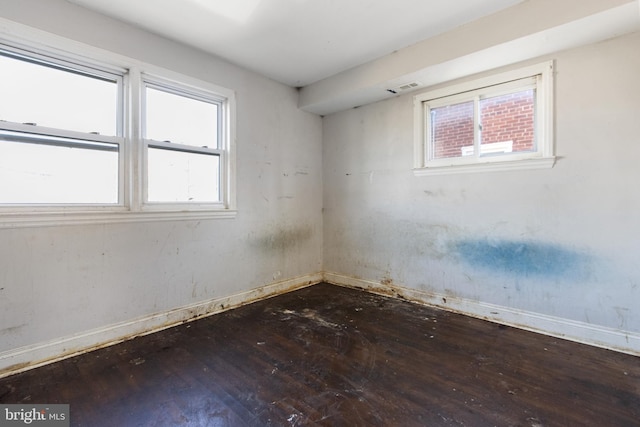 empty room with dark hardwood / wood-style floors and a wealth of natural light