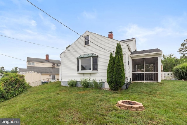 back of house with a sunroom, a yard, and an outdoor fire pit