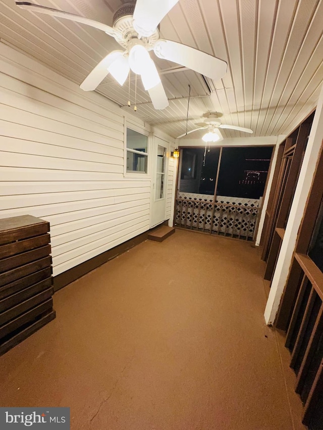 interior space with carpet flooring, ceiling fan, and wooden walls