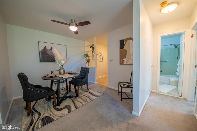 dining space with ceiling fan and light colored carpet