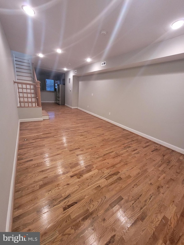 basement featuring wood-type flooring and stainless steel refrigerator