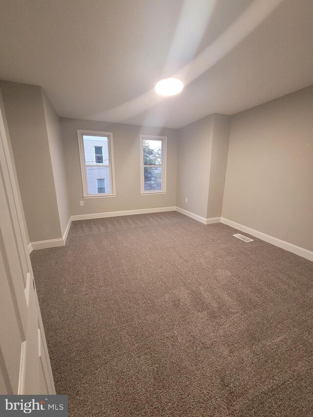 unfurnished room with dark carpet