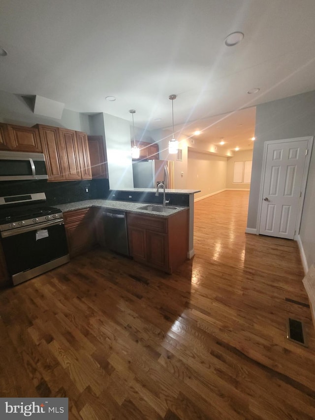 kitchen featuring sink, hanging light fixtures, dark hardwood / wood-style floors, appliances with stainless steel finishes, and kitchen peninsula