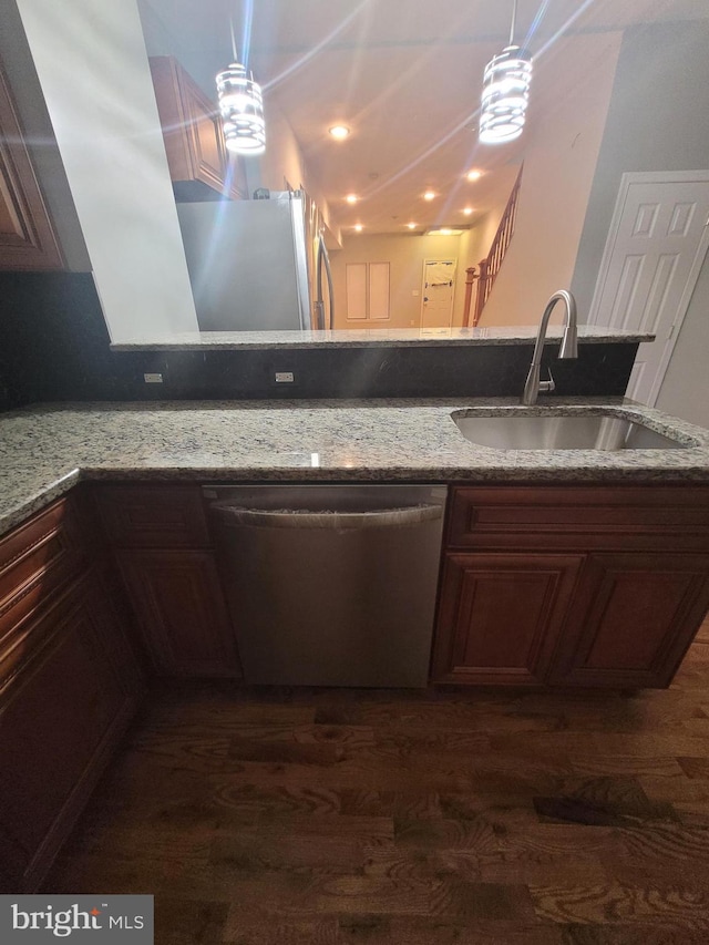 kitchen with appliances with stainless steel finishes, light stone counters, dark wood-type flooring, sink, and decorative light fixtures