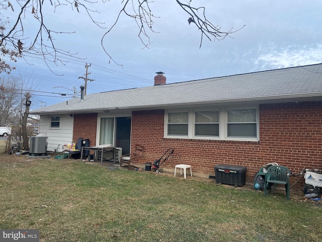 rear view of house featuring a yard and central air condition unit