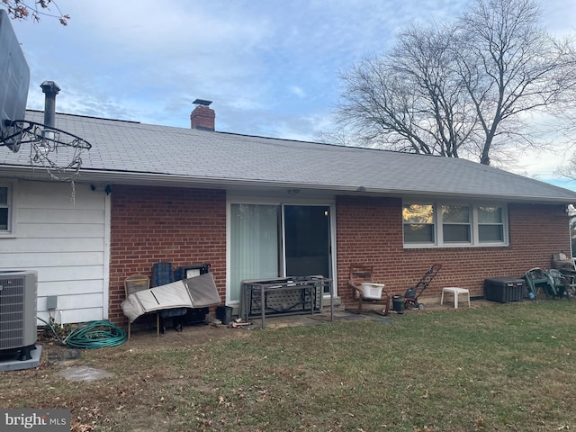 rear view of property with a yard and central air condition unit