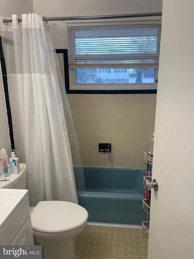 full bathroom featuring tile patterned flooring, shower / bath combo with shower curtain, vanity, and toilet